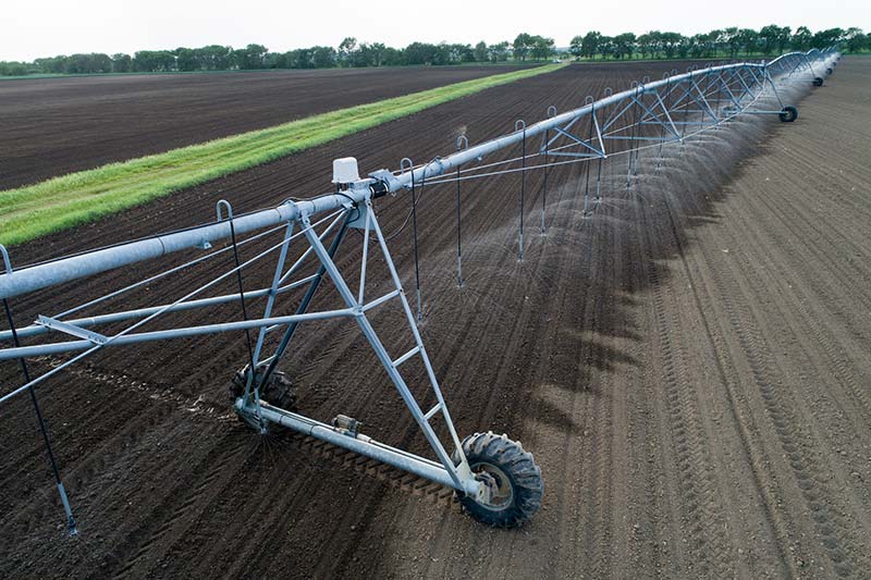 farm irrigation equipment watering a row of crops