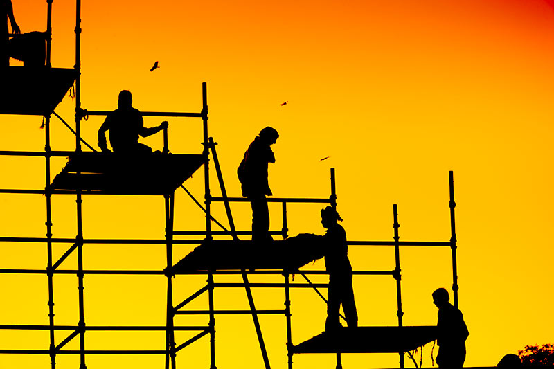 construction workers on scaffolding at sunset