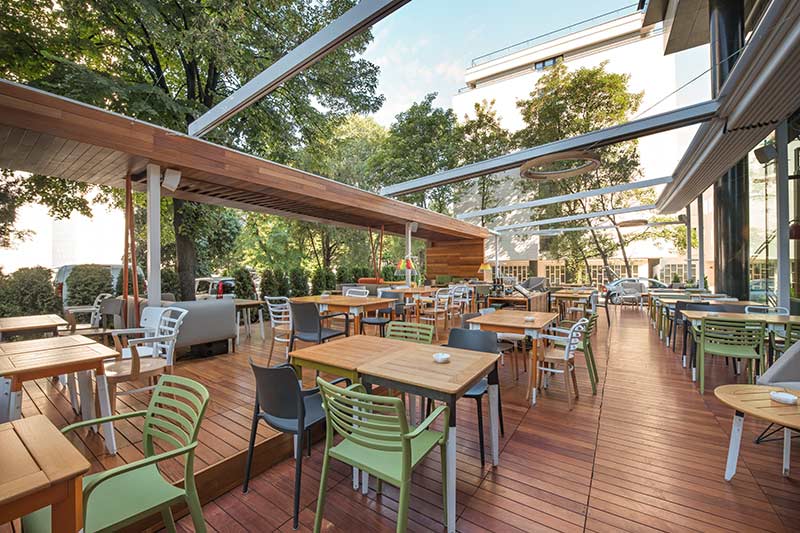 beautiful out door restaurant with teak wood tables and colorful chairs