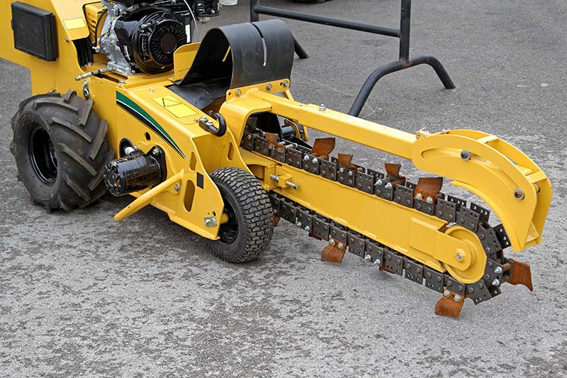 yellow trencher ready to trench pavement