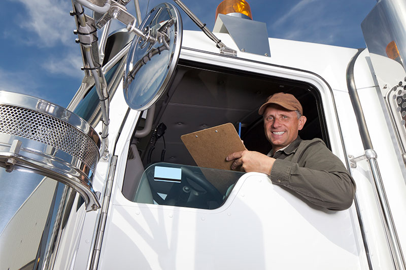 trucking business owner in a white flatbed trailer cab