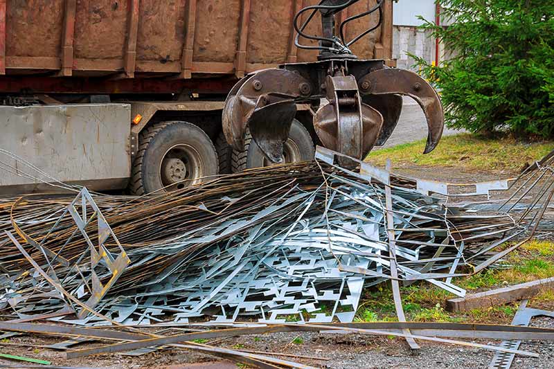 grapple truck collecting pile of scrap metal