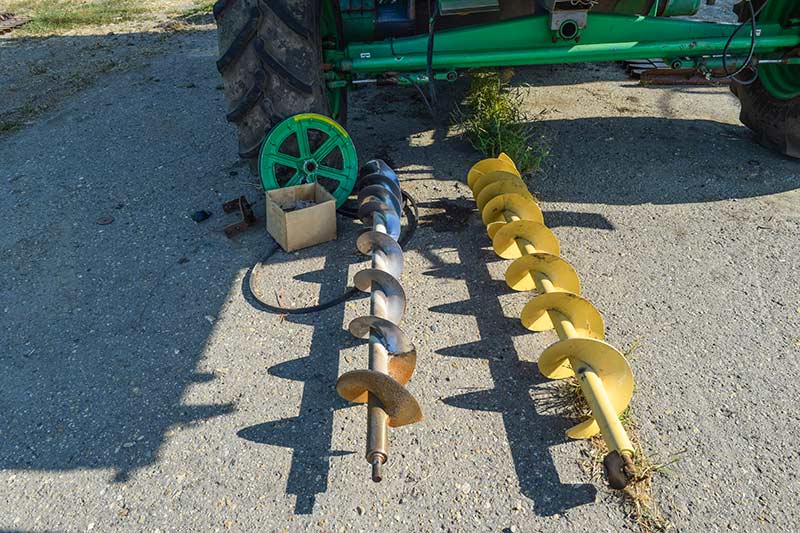 two large augers next to a green tractor