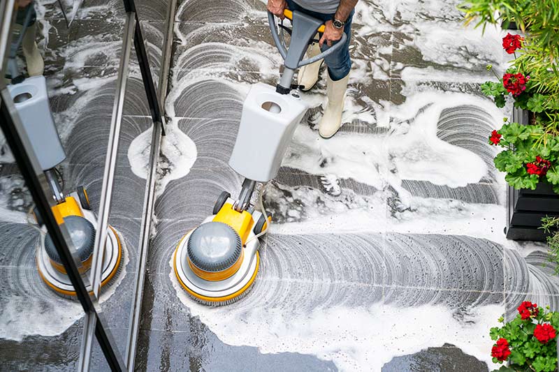 franchise cleaning worker cleaning floors with power cleaning equipment