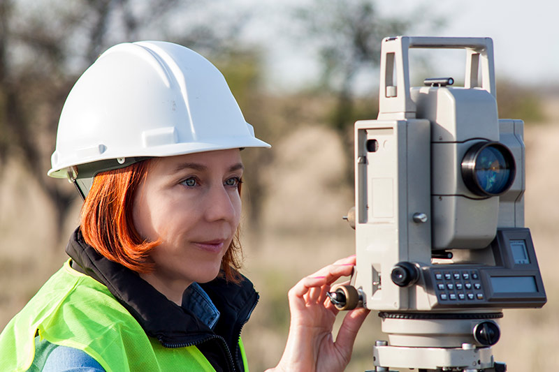 female land surveyor operating a total station at jobsite