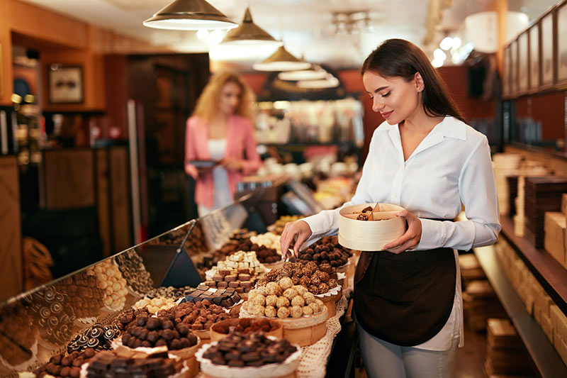 female chocolate business owner gathering up chocolates for customer