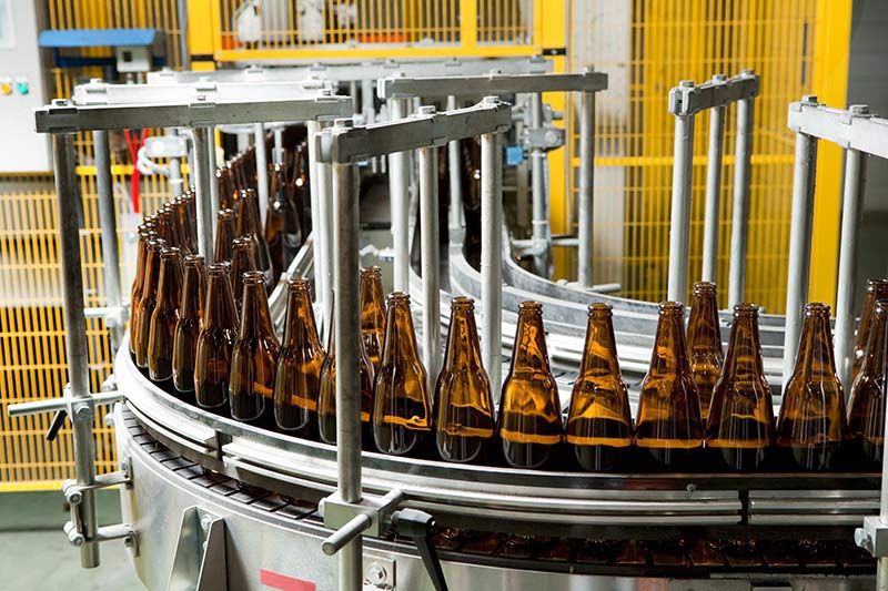 bottling equipment financing, large brown bottles on conveyor belt