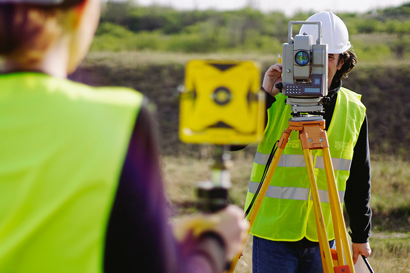 two land surveyors setting up equipment at job site, surveying equipment vendor financing