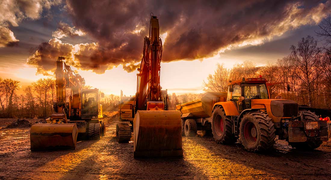 heavy equipment at a job site with a beautiful sunset sky, five reasons to finance heavy equipment